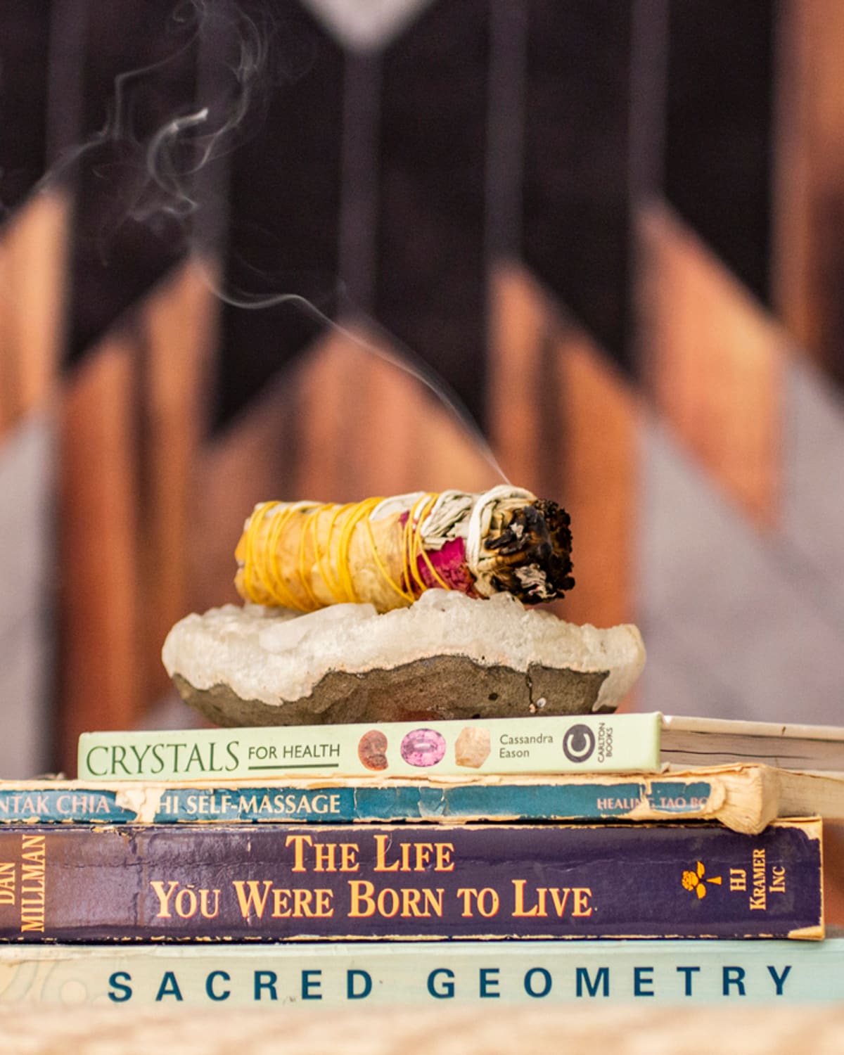 A smudge stick resting on a crystal dish atop a stack of healing books in the studio