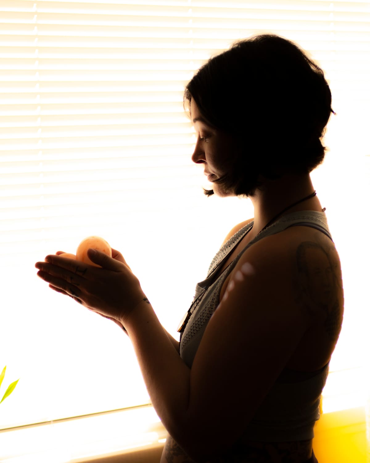Chelsea silhouetted at a sunlit window, holding crystals in both hands